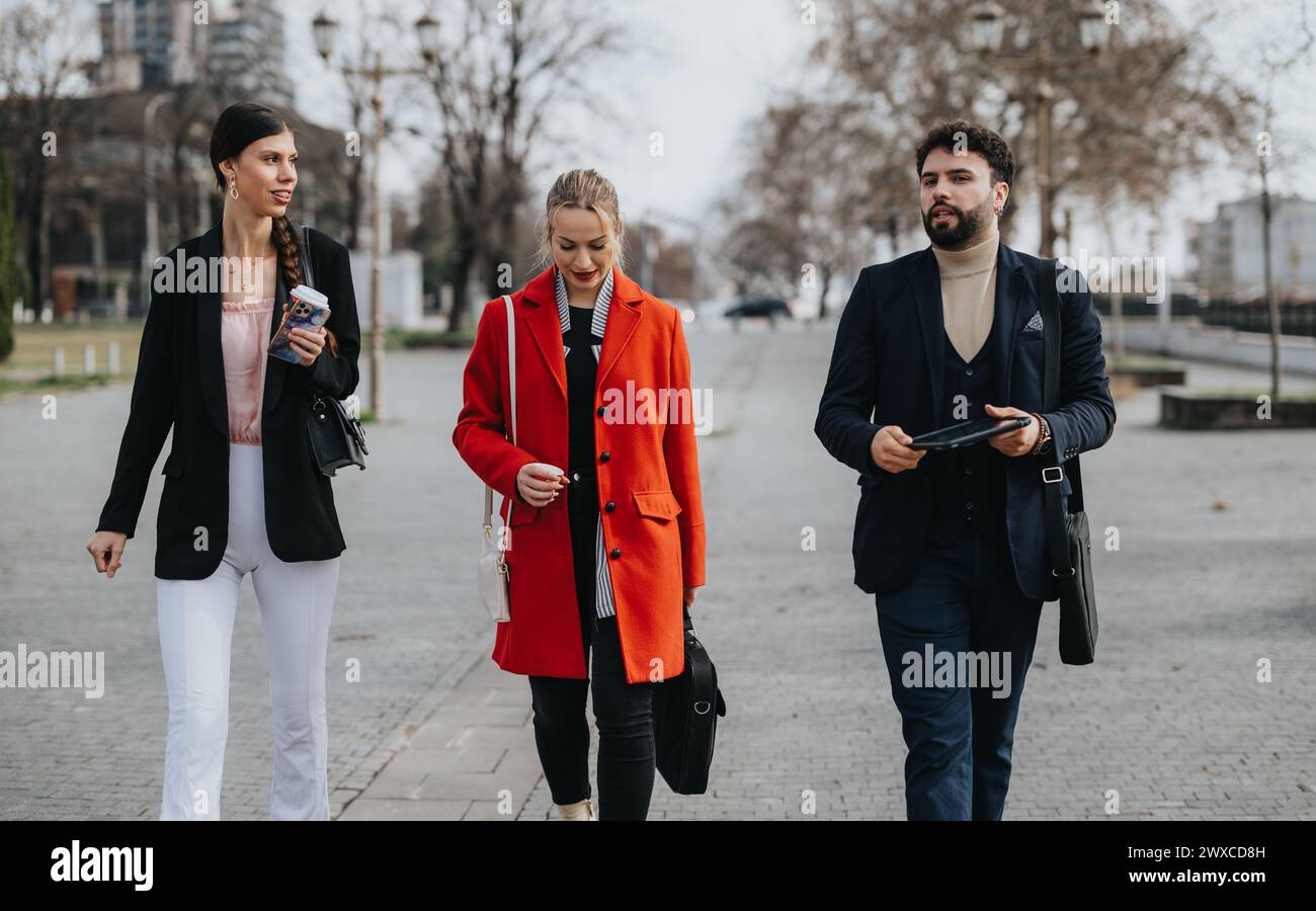 Three business professionals walking outdoors in casual conversation Stock Photo