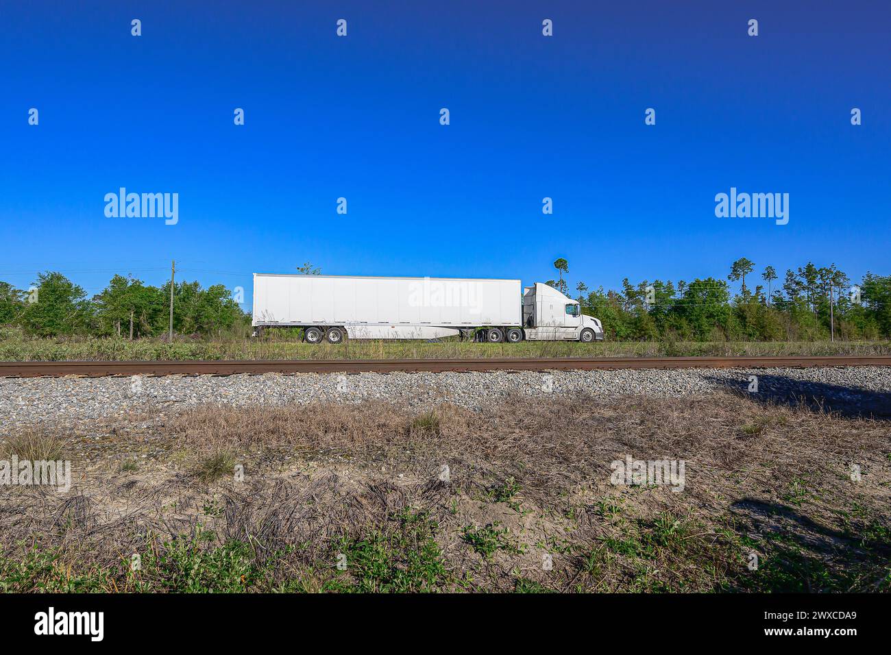 quot Boundless routes A colossal 18 wheeler - Boundless Routes A Colossal 18 Wheeler Tractor Trailer Traverses The Highway As Railroad Tracks Stretch In The Foreground Against The Backdrop Of A 2WXCDA9 