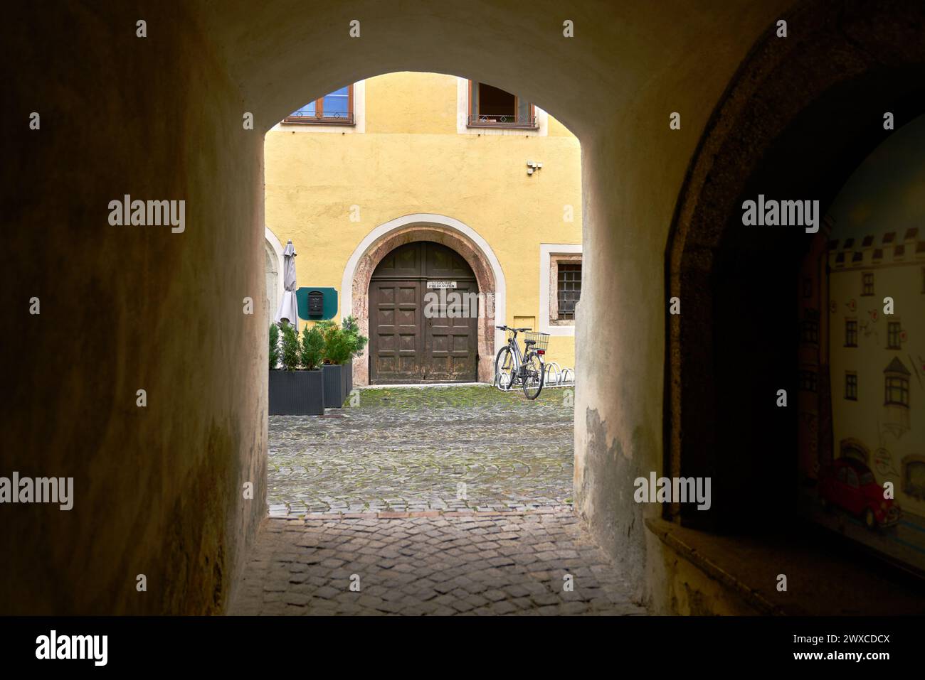 Old Arched Doorway in Europe. A doorway onto a lane at the end of a passageway in a historic medieval European town. Stock Photo