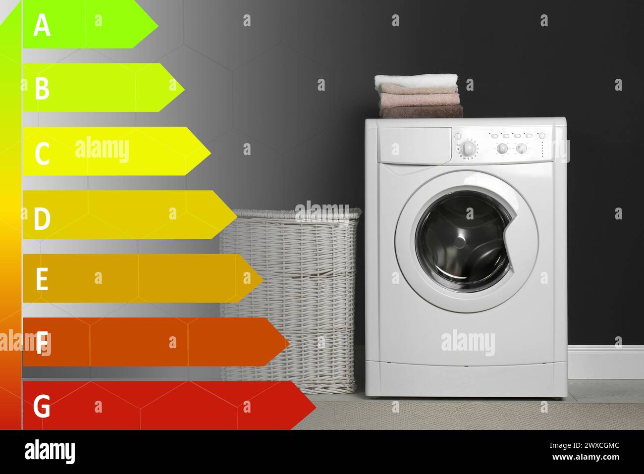 Energy efficiency rating label and washing machine with laundry near black wall indoors Stock Photo