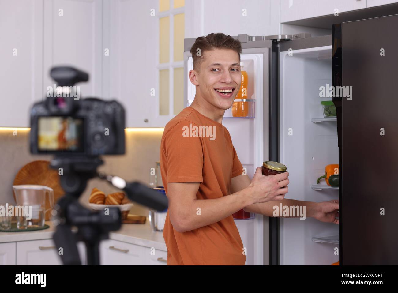 Smiling food blogger explaining something while recording video in kitchen Stock Photo