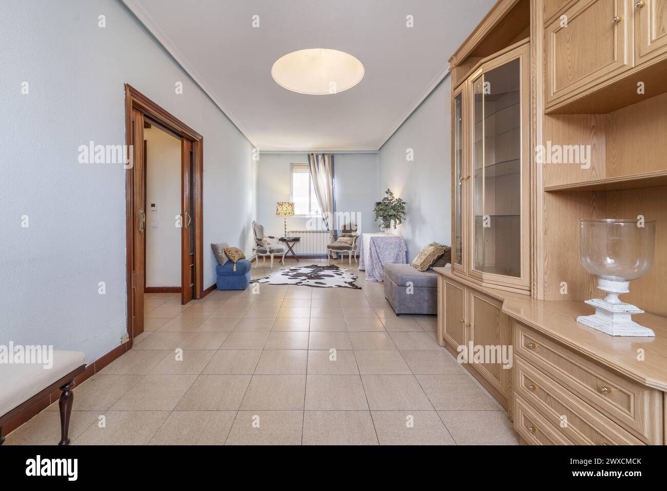 Living room of a semi-furnished house with a light wood bookcase and some Louis XV style armchairs Stock Photo