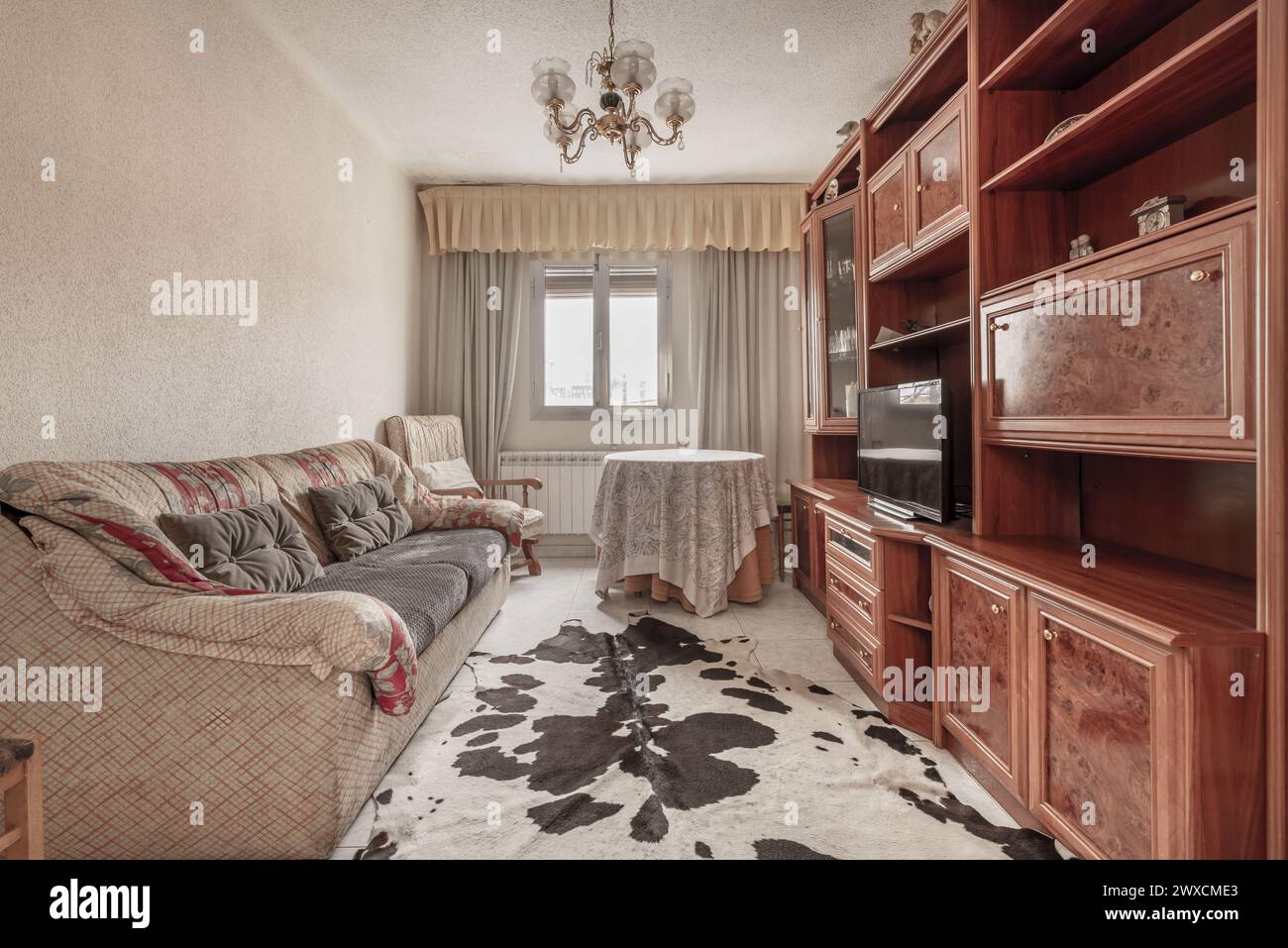 living room of a house with sofas made of old and dirty colored fabric and a floor covered with synthetic cowhide Stock Photo