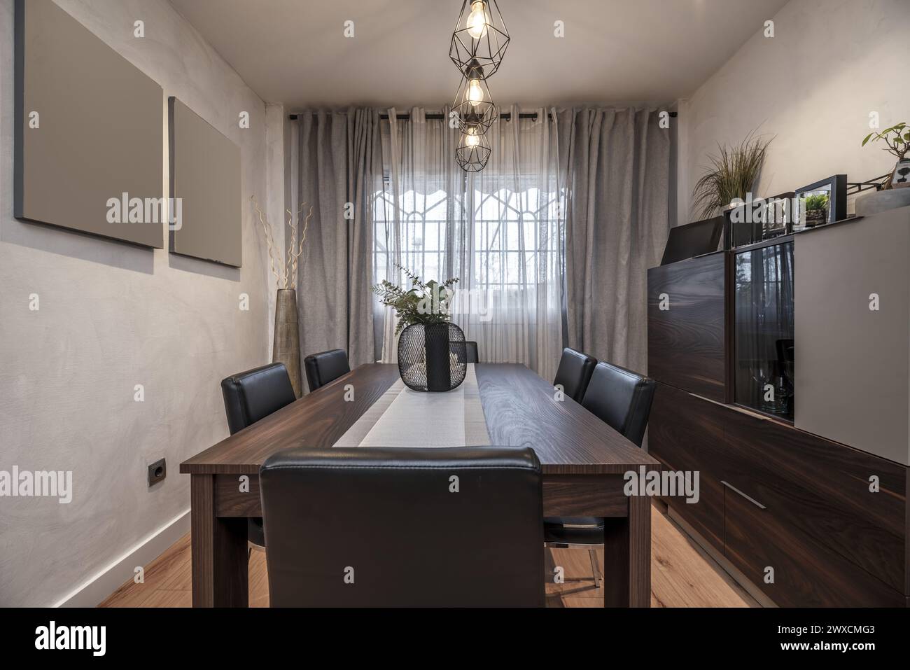 Living room with dark wood dining table matching bookcase and black upholstered chairs Stock Photo