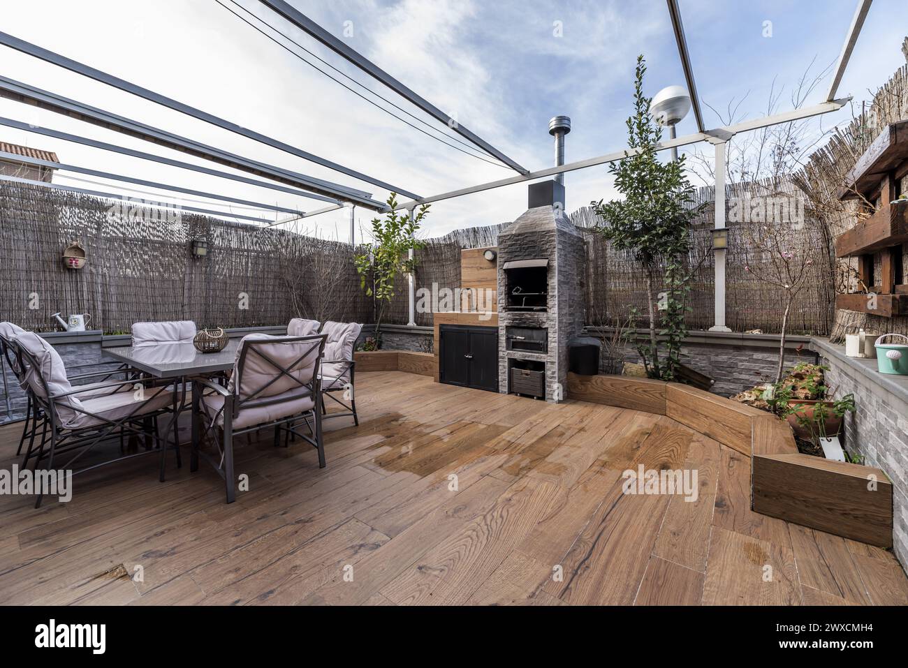 a plant-filled terrace with smooth metal furniture and wicker dividers ...