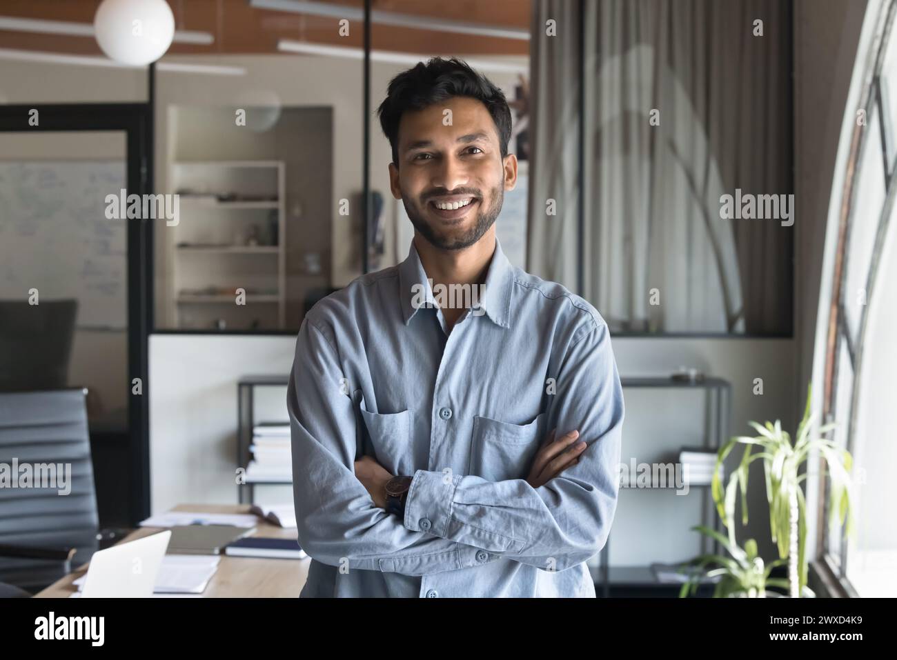Happy successful attractive Indian business man standing in office Stock Photo