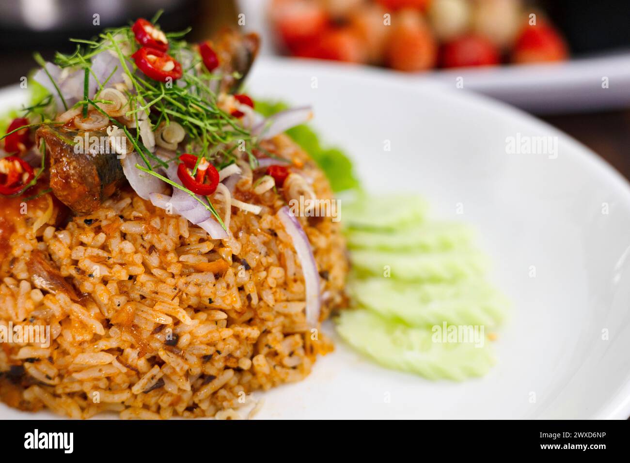Thai food, Fried jasmine rice with canned fish mackerel in tomato sauce, topped with red chili, red onion, lettuce and kaffir lime leaves. Stock Photo