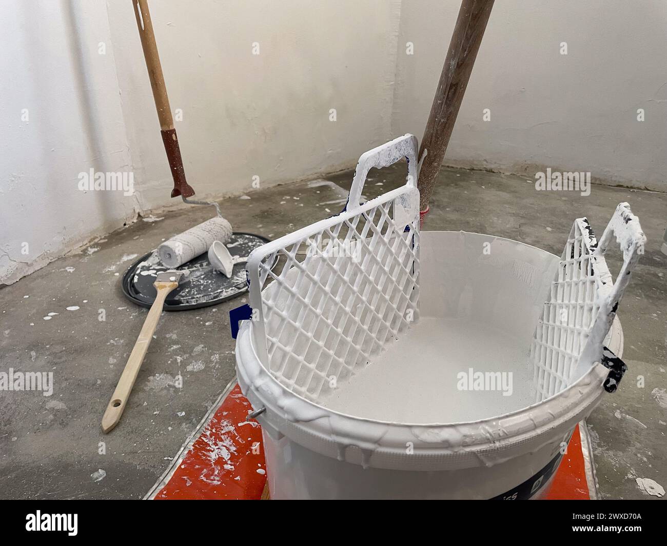 Paint bucket with brush and white paint in a room during renovation ...