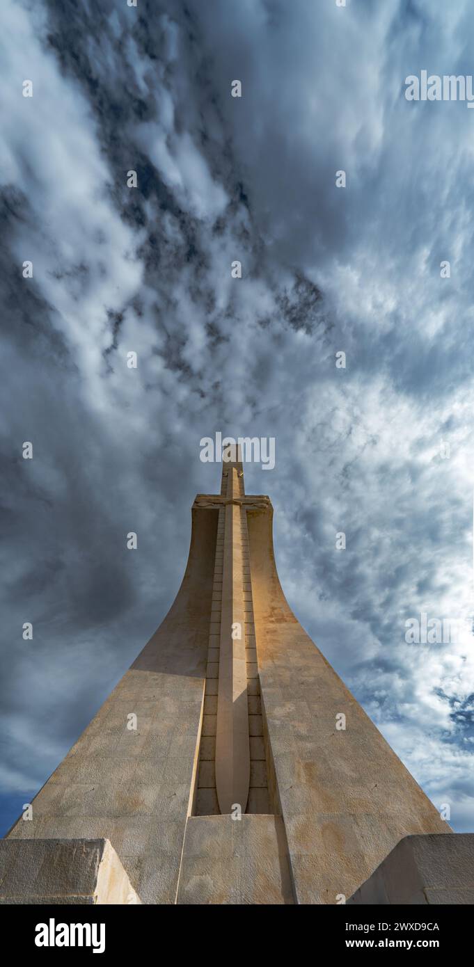 Low angle front view of the Monument to the Discoveries in Lisbon with a spectacular cloudy blue sky with the evening light illuminating the stone swo Stock Photo