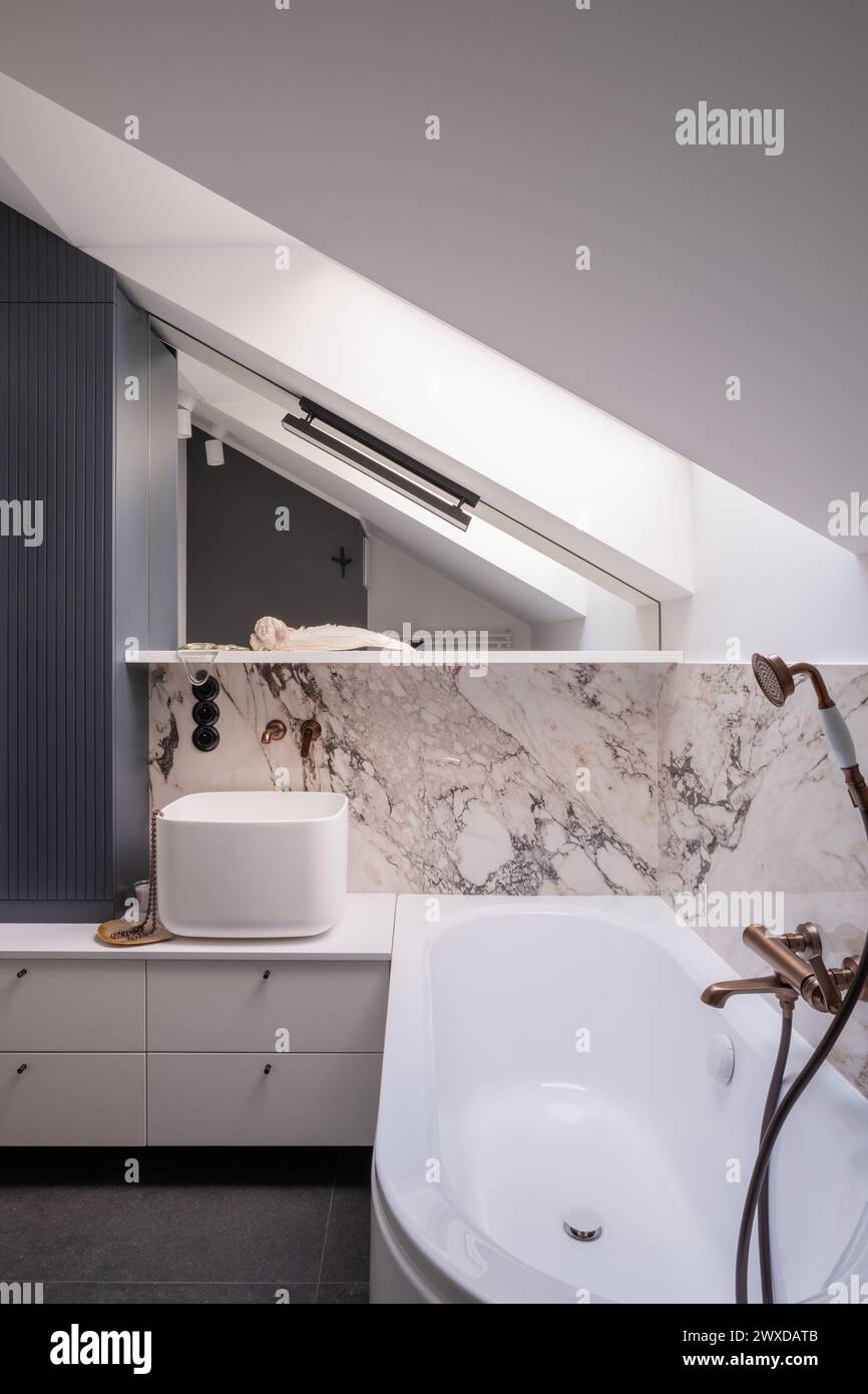 Bathroom in a building with bathtub, sink, mirror, and wood fixtures Stock Photo