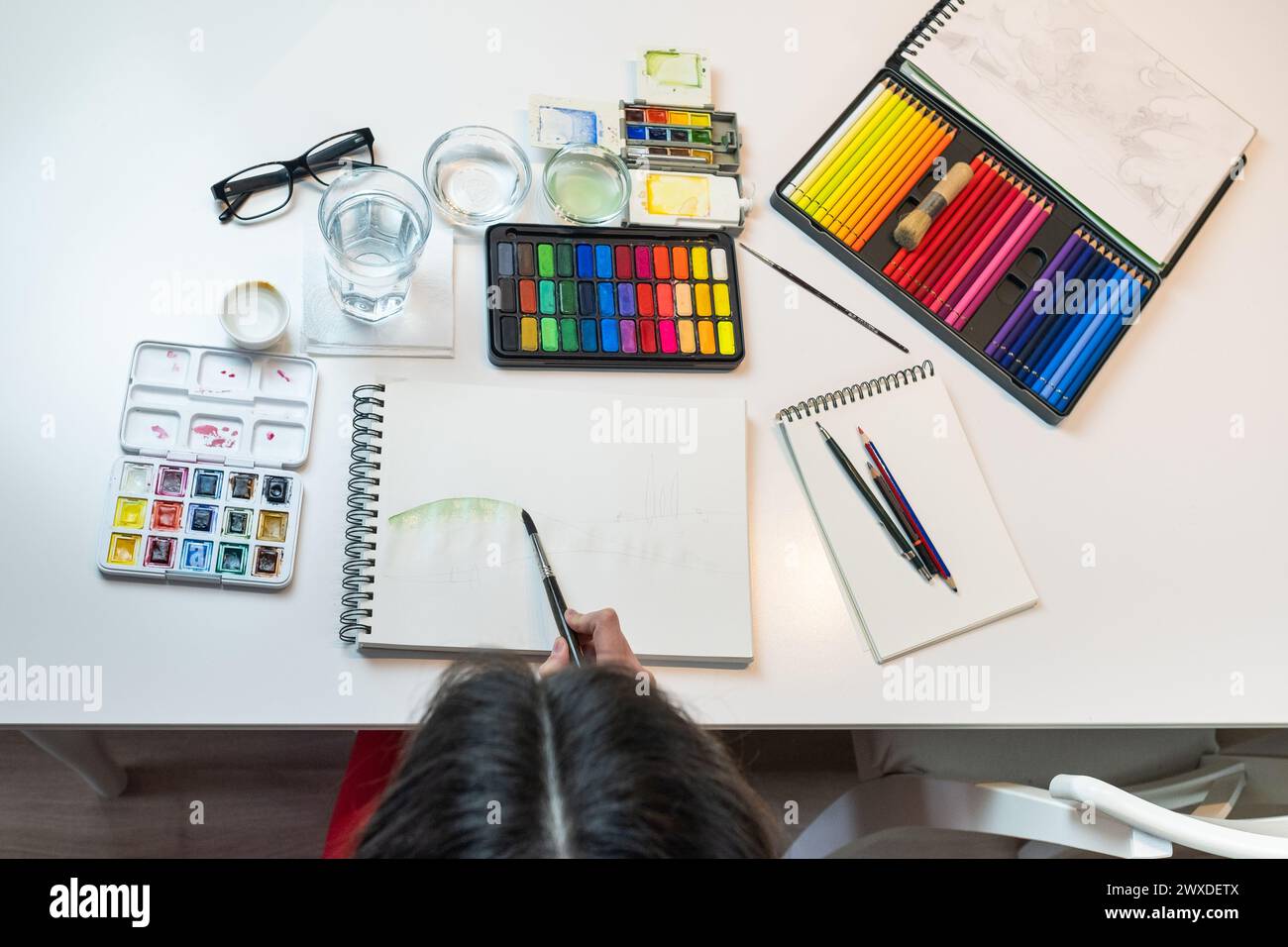 top view of a woman painting Watercolors from above, working utensils ...