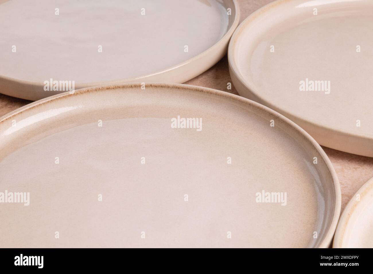 Beige ceramic dinner plates on a brown stone tabletop. Stock Photo