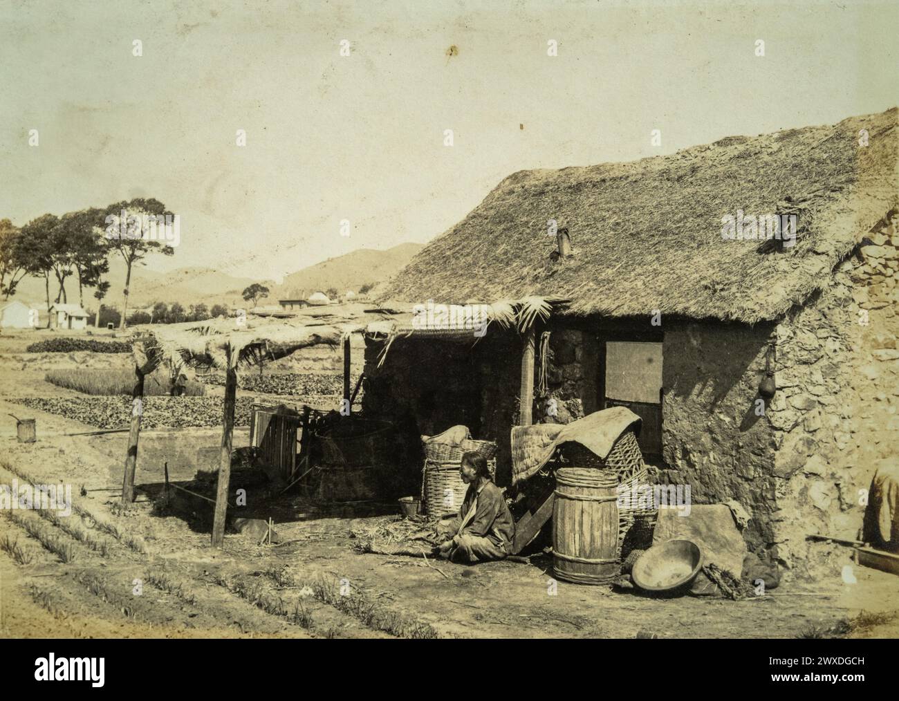 Historic photograph of a farmer's thatched house and fields in Northeast China (Manchuria) in the 1930s and 1940s. Stock Photo