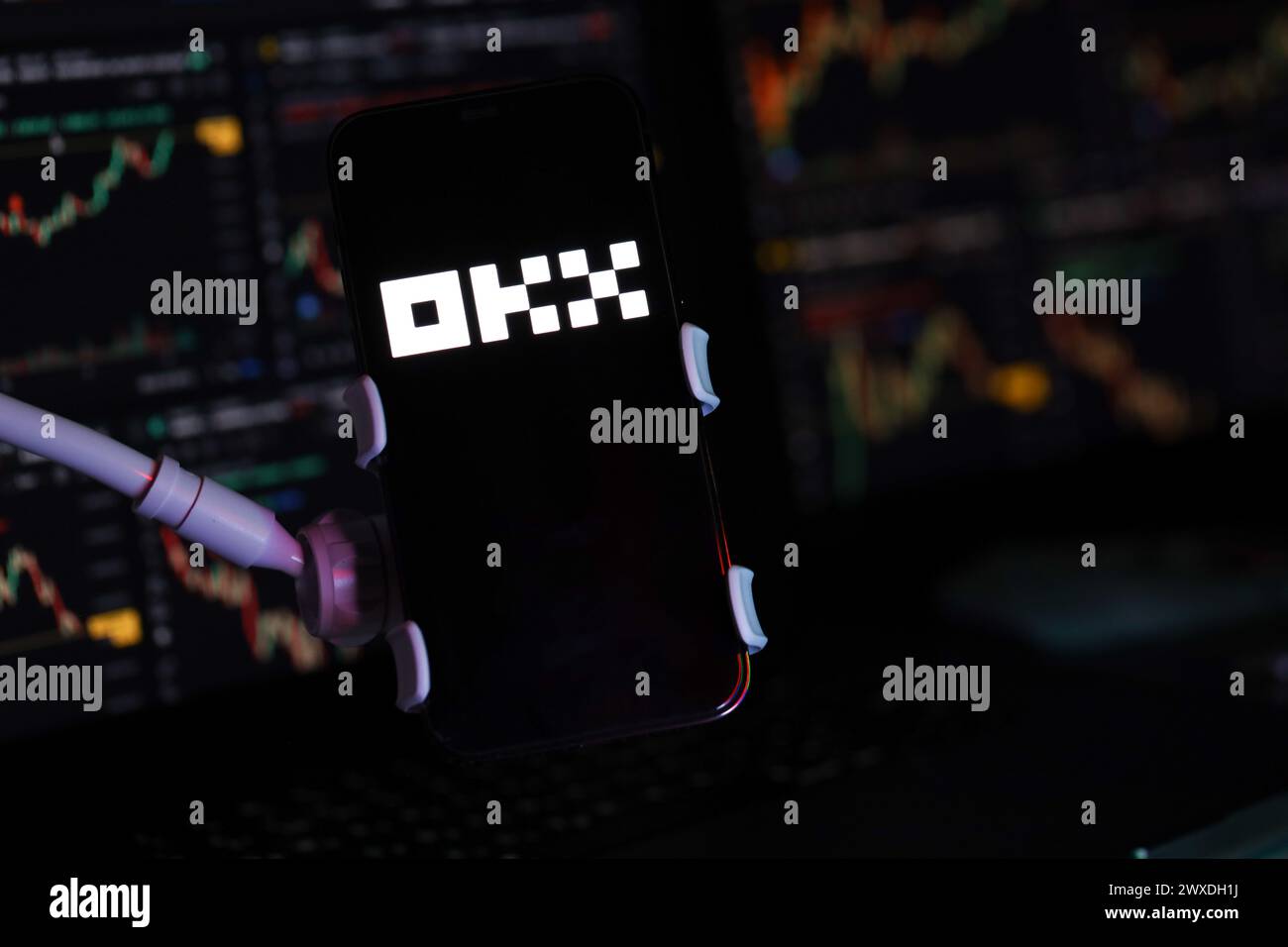 KYIV, UKRAINE - MARCH 15, 2024 OKX logo on iPhone display screen and crypto currency value charts. Cryptocurrency exchange portal Stock Photo