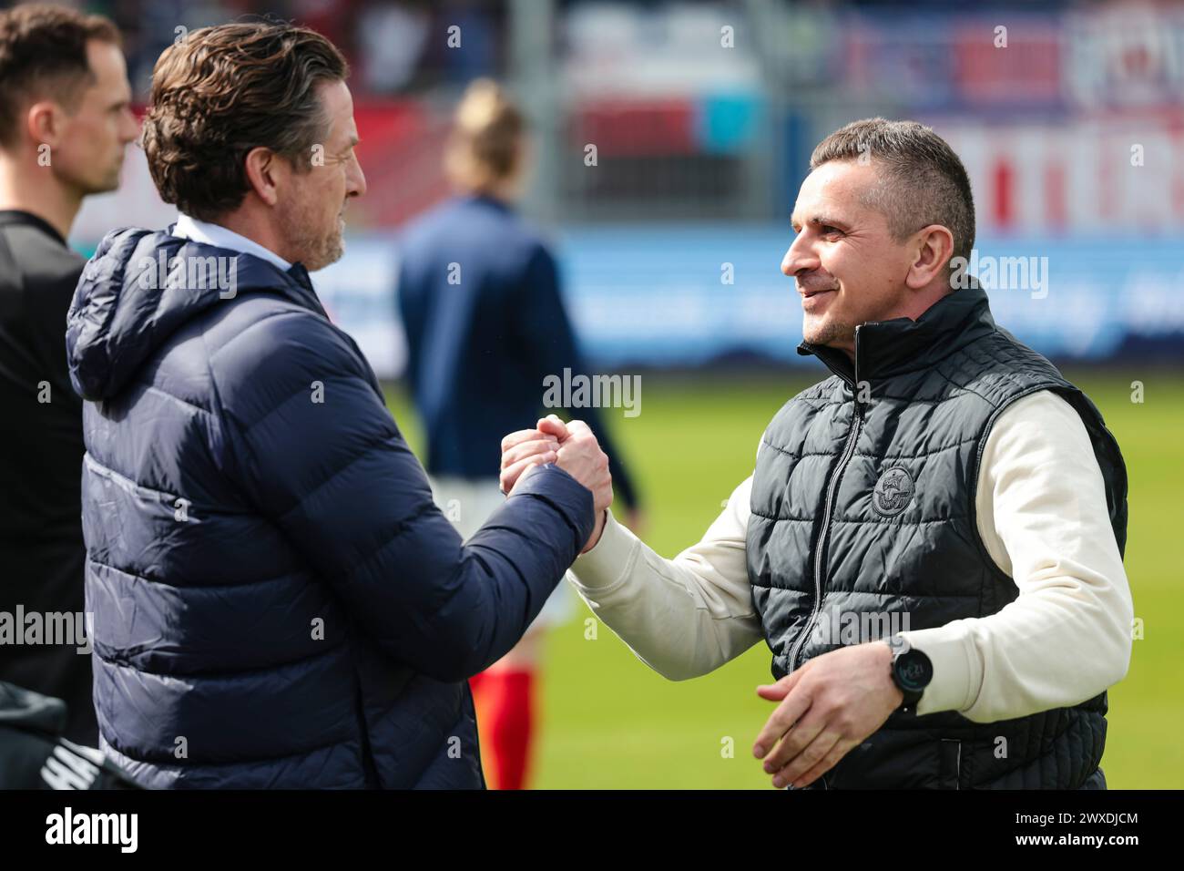 Kiel, Germany. 30th Mar, 2024. Soccer: Bundesliga 2, Holstein Kiel - Hansa Rostock, Matchday 27, Holstein Stadium. Carsten Wehlmann (l), Managing Director Sport at Holstein Kiel, and Rostock coach Mersad Selimbegovic greet each other. Credit: Frank Molter/dpa - IMPORTANT NOTE: In accordance with the regulations of the DFL German Football League and the DFB German Football Association, it is prohibited to utilize or have utilized photographs taken in the stadium and/or of the match in the form of sequential images and/or video-like photo series./dpa/Alamy Live News Stock Photo