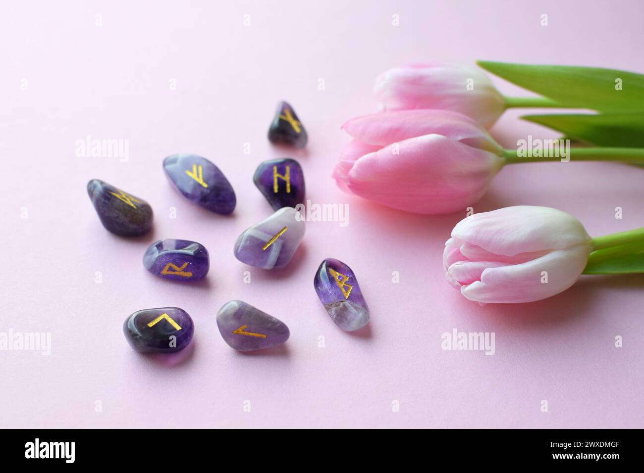 Scandinavian runes made of amethyst and a bouquet of pink tulips Stock Photo