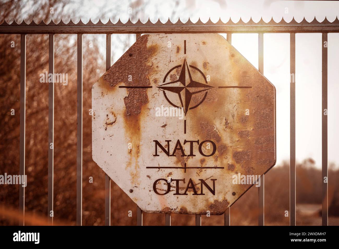 March 30, 2024: Rusty sign on a barrier fence with NATO logo. Symbolic image of a NATO war zone. PHOTOMONTAGE *** Rostiges Schild an einem Absperrzaun mit NATO Logo. Symbolbild Kriegsgebiet der NATO. FOTOMONTAGE Stock Photo