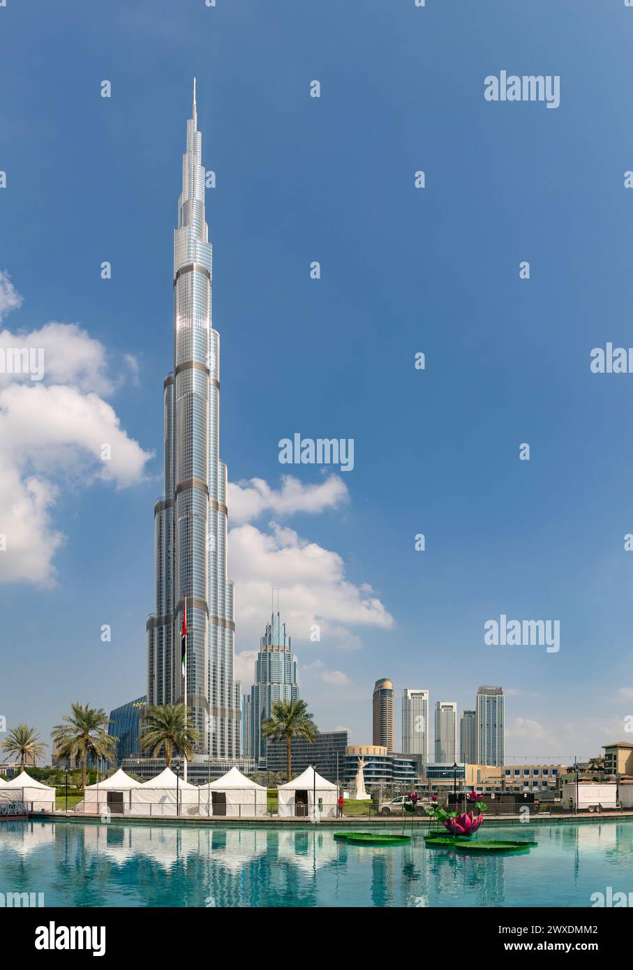 A picture of the Burj Khalifa towering the nearby Downtown Dubai buildings and the blue waters of the Burj Khalifa Lake. Stock Photo