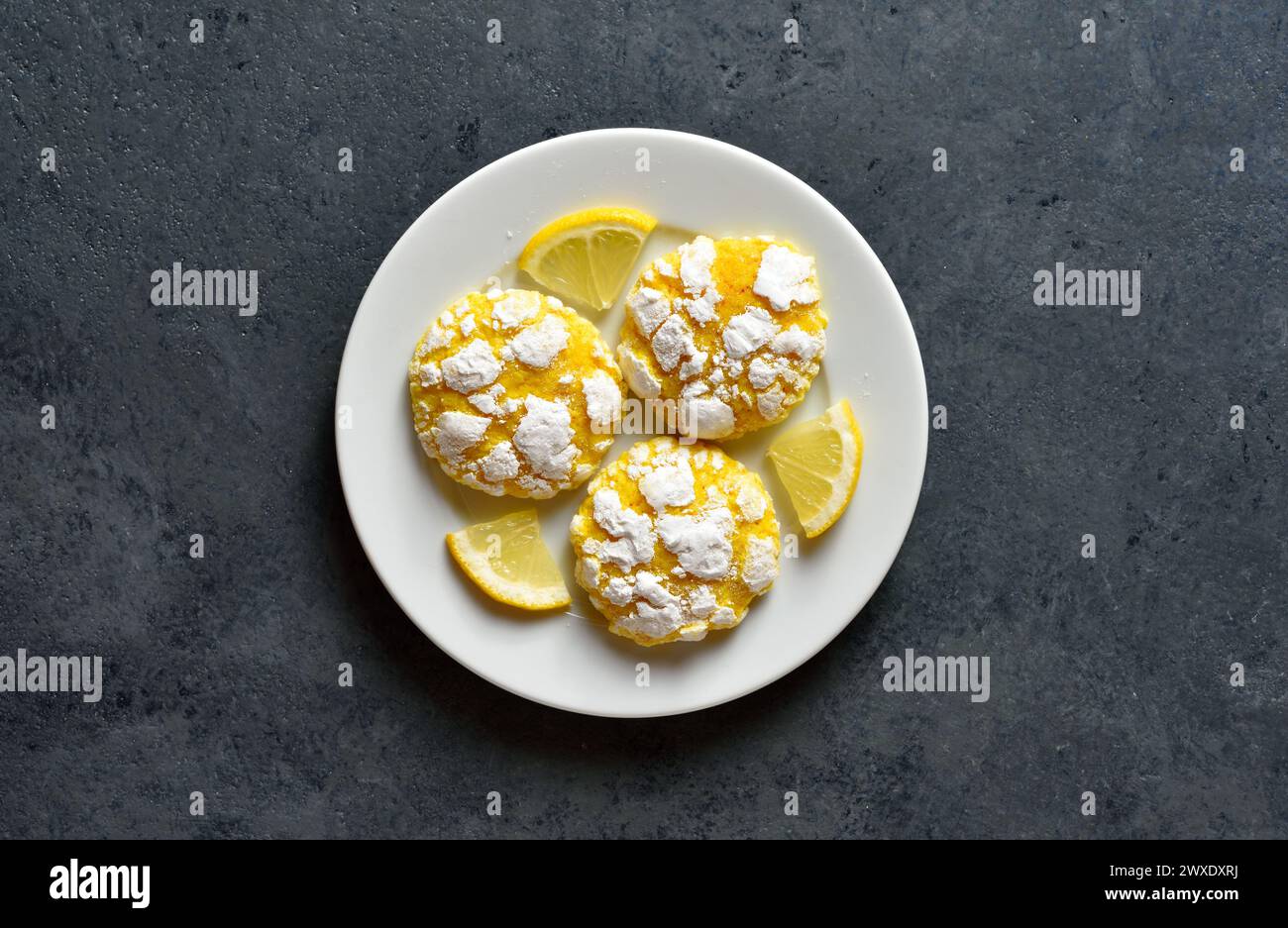 Lemon crinkle cookies on plate over dark stone background. Top view, flat lay Stock Photo
