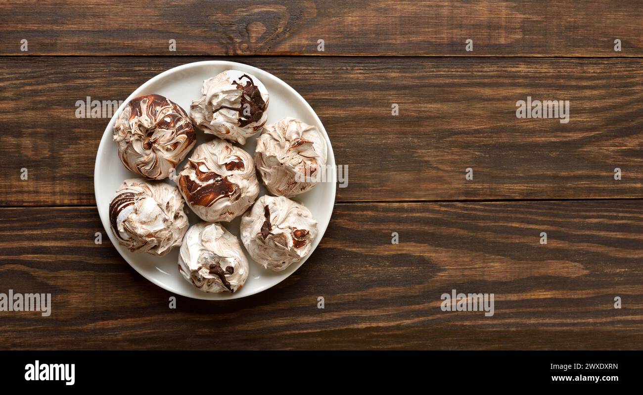 Chocolate meringue cookies on plate over wooden background with free space. Top view, flat lay Stock Photo