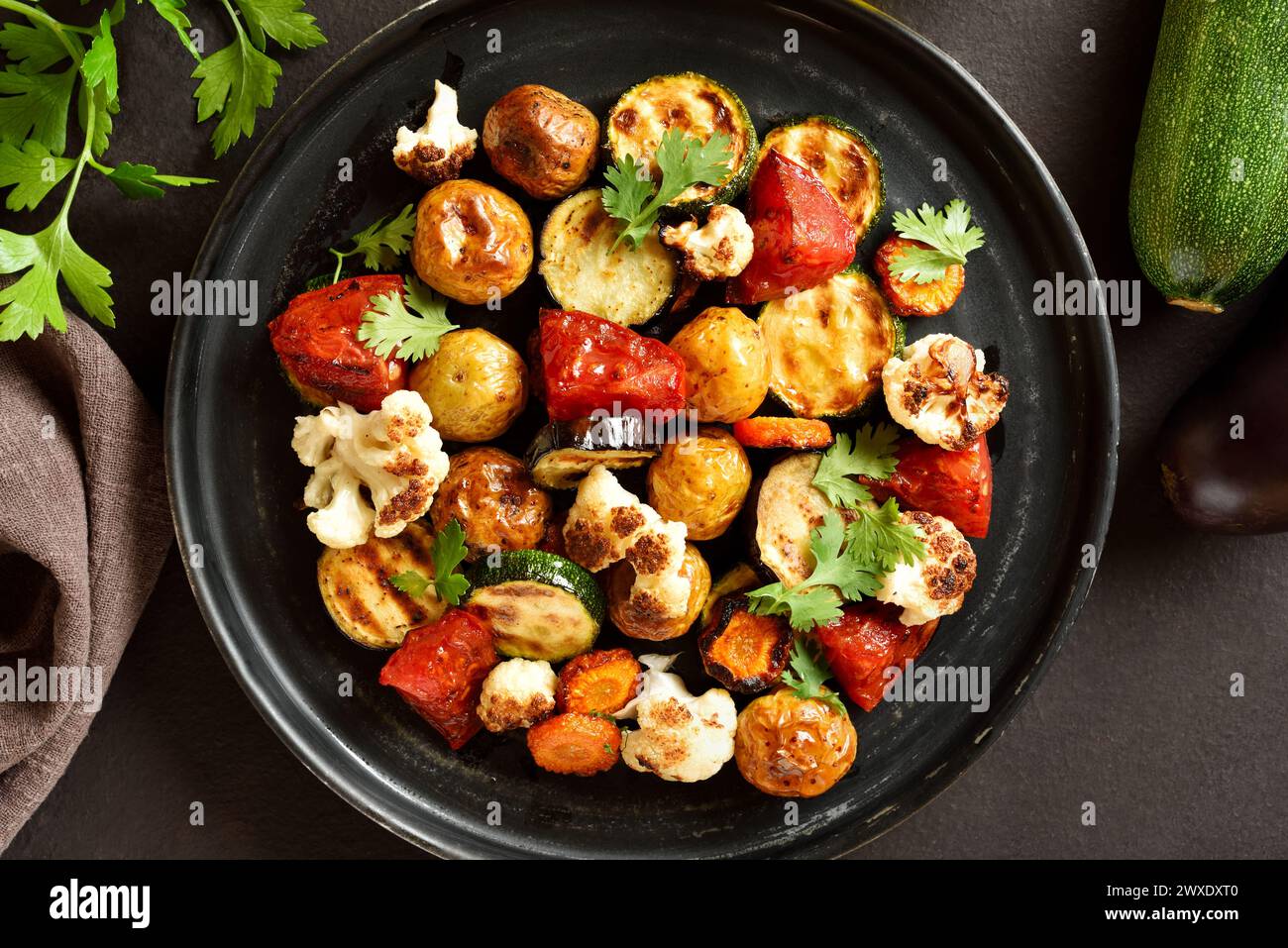 Roasted vegetables on plate over dark background. Top view, flat lay Stock Photo