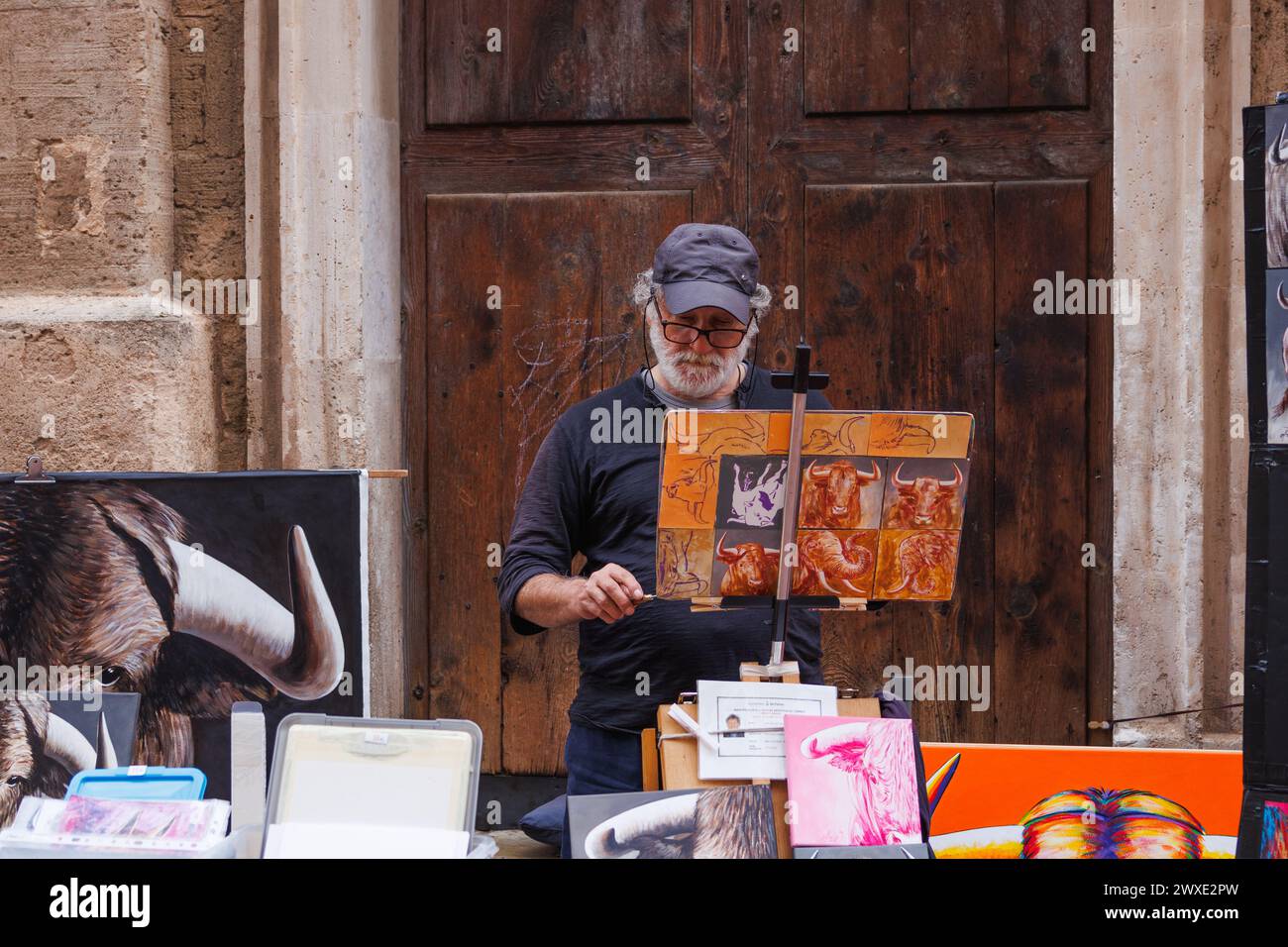 Palma de Mallorca, Spain - April 29, 2023: Senior man street artist paints on canvas in Palma de Mallorca city center and sells his paintings Stock Photo