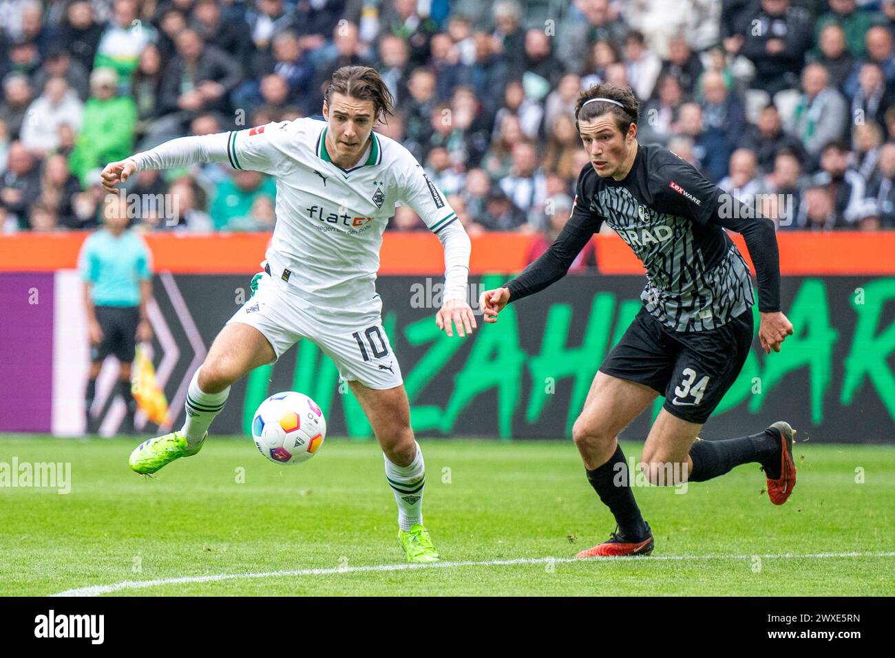 30 March 2024, North Rhine-Westphalia, Mönchengladbach: Soccer: Bundesliga, Bor. Mönchengladbach - SC Freiburg, Matchday 27, Stadion im Borussia-Park: Gladbach's Florian Neuhaus (l) and Freiburg's Merlin Röhl fight for the ball. Photo: David Inderlied/dpa - IMPORTANT NOTE: In accordance with the regulations of the DFL German Football League and the DFB German Football Association, it is prohibited to utilize or have utilized photographs taken in the stadium and/or of the match in the form of sequential images and/or video-like photo series. Stock Photo