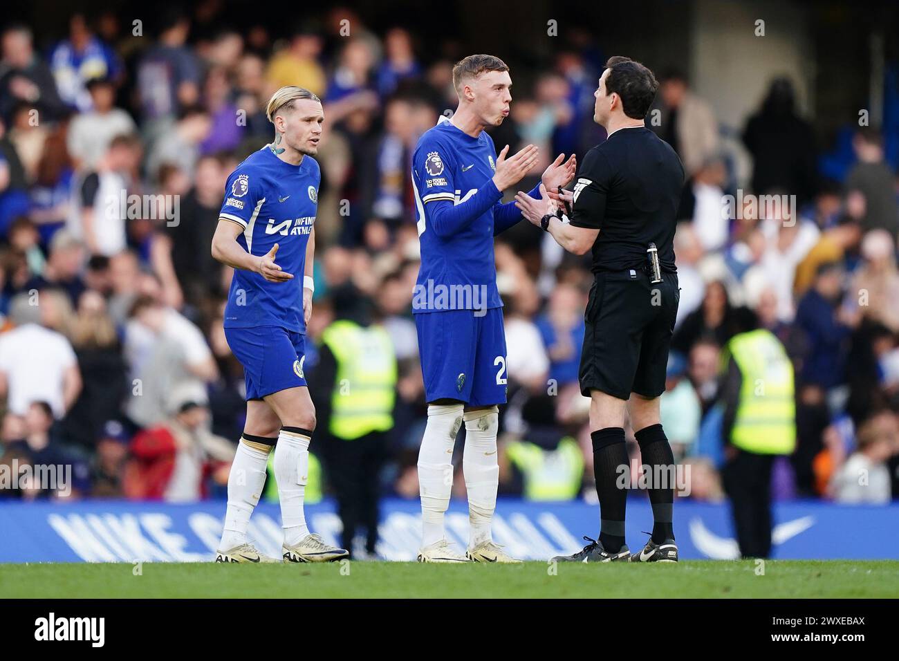 Chelsea's Mykhaylo Mudryk (left) and Cole Palmer speak to referee Darren England (right) after the final whistle in the Premier League match at Stamford Bridge, London. Picture date: Saturday March 30, 2024. Stock Photo