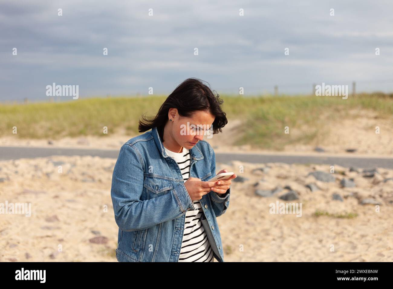 Woman using mobile phone on the beach in summer with blue sky ...