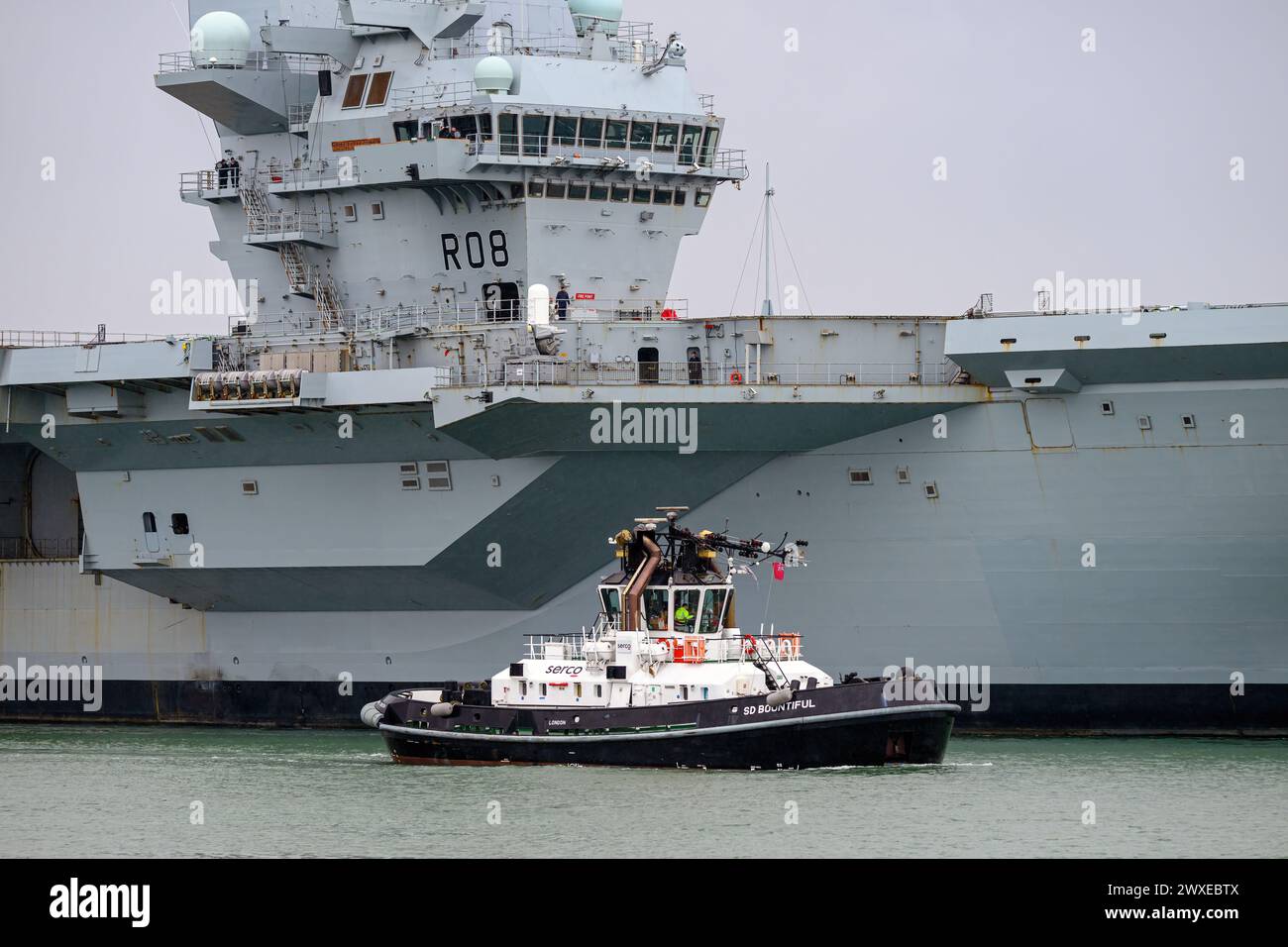 The Serco Marine Damen ATD 2909 tug SD Bountiful assisting with the movement of a Royal Navy warship at Portsmouth. Stock Photo