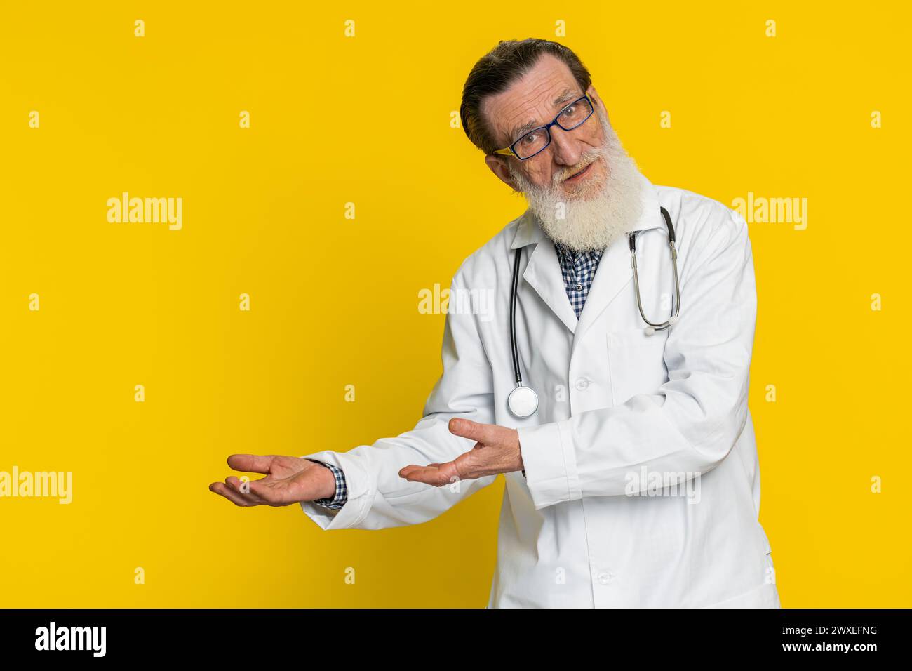 Senior elderly doctor cardiologist man raising hands asking what why reason of failure demonstrating disbelief irritation by troubles. Apothecary pharmacy old grandfather isolated on yellow background Stock Photo