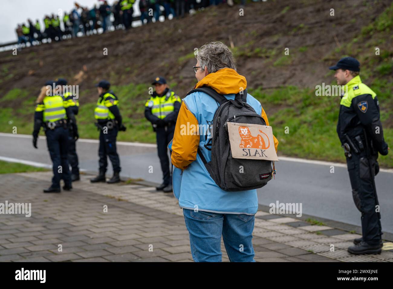 Amsterdam, The Netherlands, 30.03.2024, Elderly climate activist with caricature of The ING Group logo on the backpack during the protest action Stock Photo