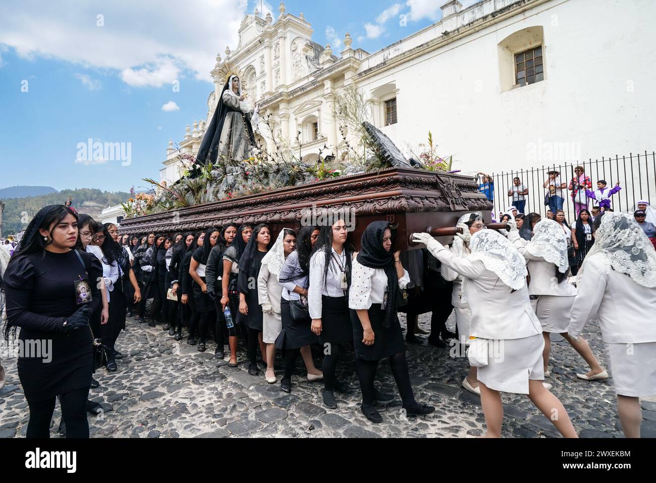 Antigua, Guatemala. 29th Mar, 2024. Women penitents carry the Virgin Mary on the massive La Merced Good Friday processional float as they pass the Cathedral San Jose during Semana Santa, March 29, 2024 in Antigua, Guatemala. The opulent processions, detailed alfombras and centuries-old traditions attract more than 1 million people to the ancient capital city. Credit: Richard Ellis/Richard Ellis/Alamy Live News Stock Photo