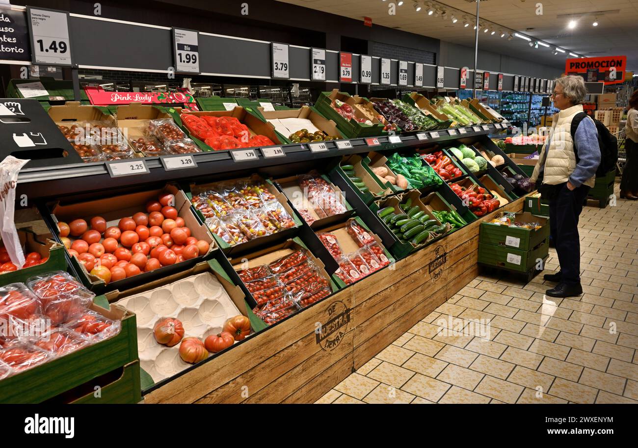 Fruit and vegetables on shelves in Lidl supermarket with customer Stock Photo