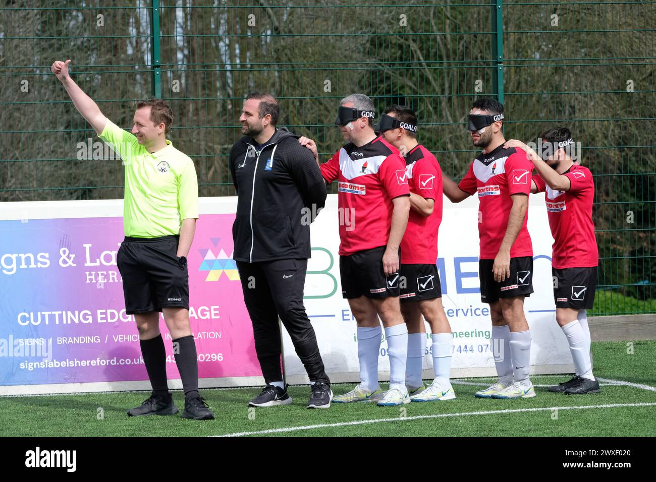 Royal National College for the Blind, Hereford, UK – Saturday 30th March 2024 – Round 3 of the European Blind Football League ( EBFL ) held at the Royal National College for the Blind at Hereford featuring six European teams. The referee leads in the Greek team Pirsos Thessaloniki at the start of their match against Borussia Dortmund of Germany. Photo Steven May / Alamy Live News Stock Photo