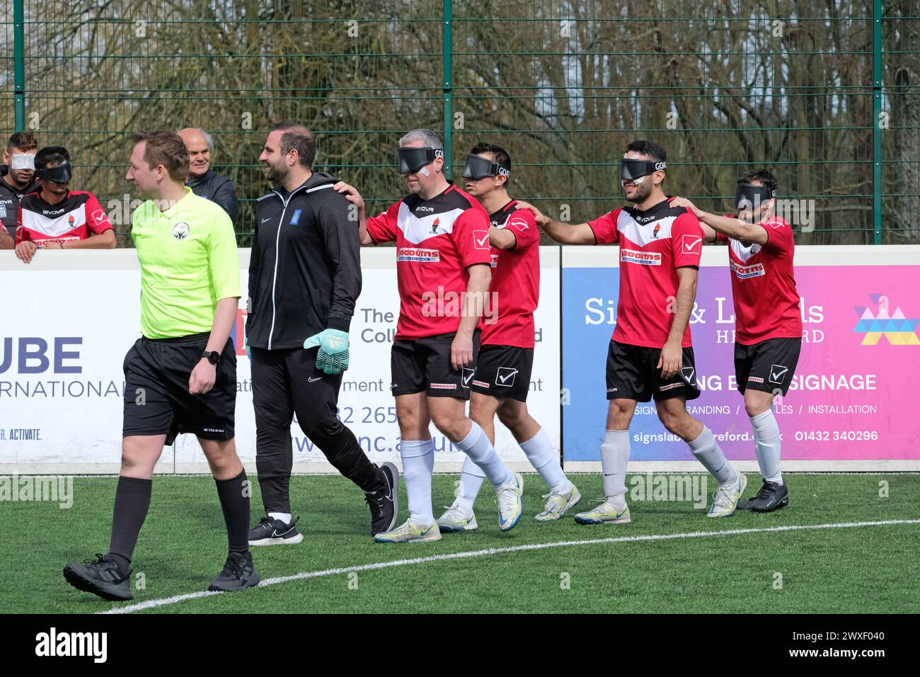 Royal National College for the Blind, Hereford, UK – Saturday 30th March 2024 – Round 3 of the European Blind Football League ( EBFL ) held at the Royal National College for the Blind at Hereford featuring six European teams. The referee leads in the Greek team Pirsos Thessaloniki at the start of their match against Borussia Dortmund of Germany. Photo Steven May / Alamy Live News Stock Photo