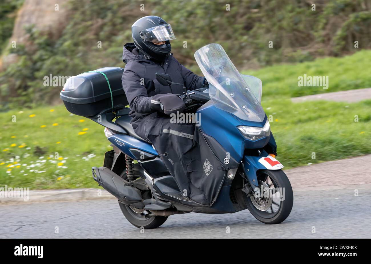 Milton Keynes,UK-Mar 30th 2024: Delivery rider on a 2021 Yamaha GPD 125 scooter, motorcycle, driving on a British road Stock Photo