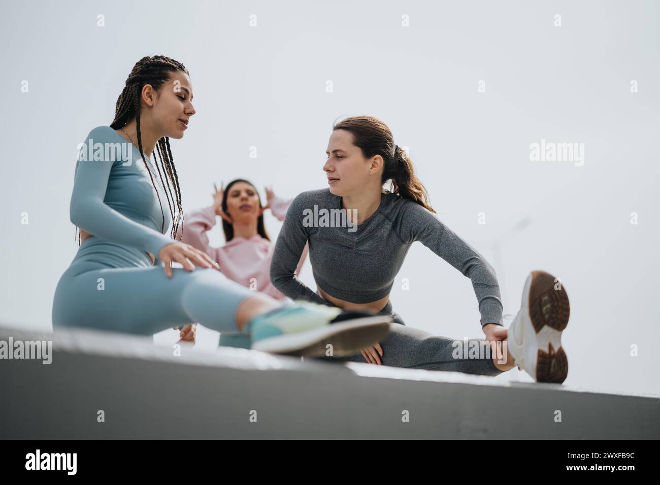 Fitness partners stretching together outdoors on a sunny day Stock Photo