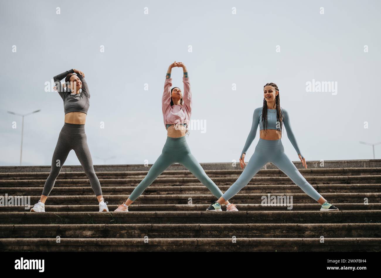 Energetic female friends stretching together on outdoor steps Stock ...