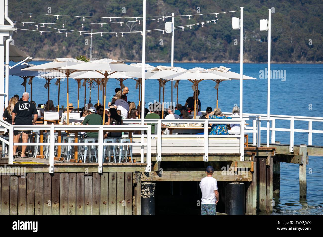 The Joey, waterfront restaurant and cafe, people sitting on timber deck enjoying lunch overlooking Pittwater, Palm Beach in Sydney,Australia,2024 Stock Photo