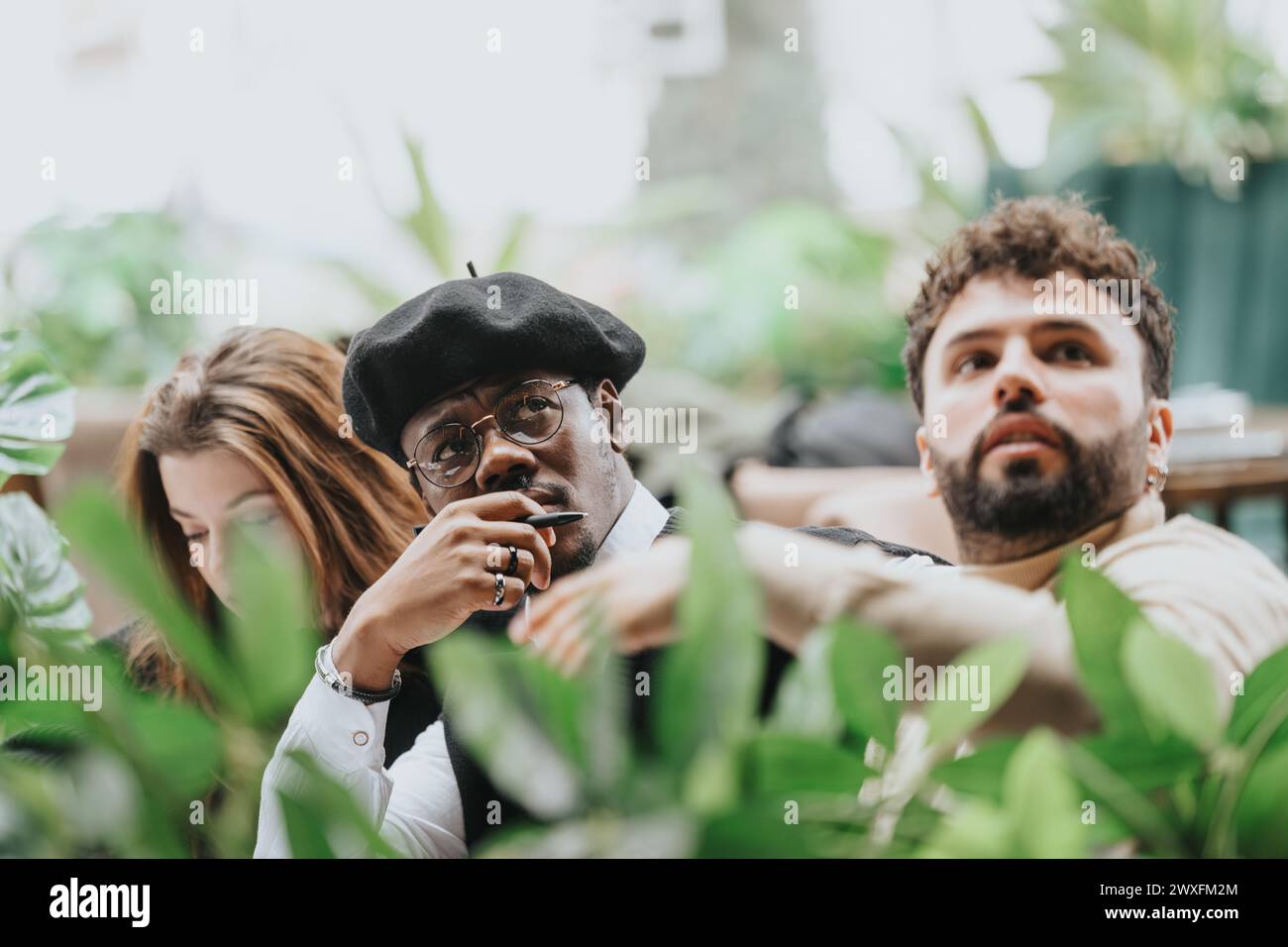 International business colleagues in a brainstorming session at a restaurant, using a laptop and engaging in a lively discussion. Stock Photo