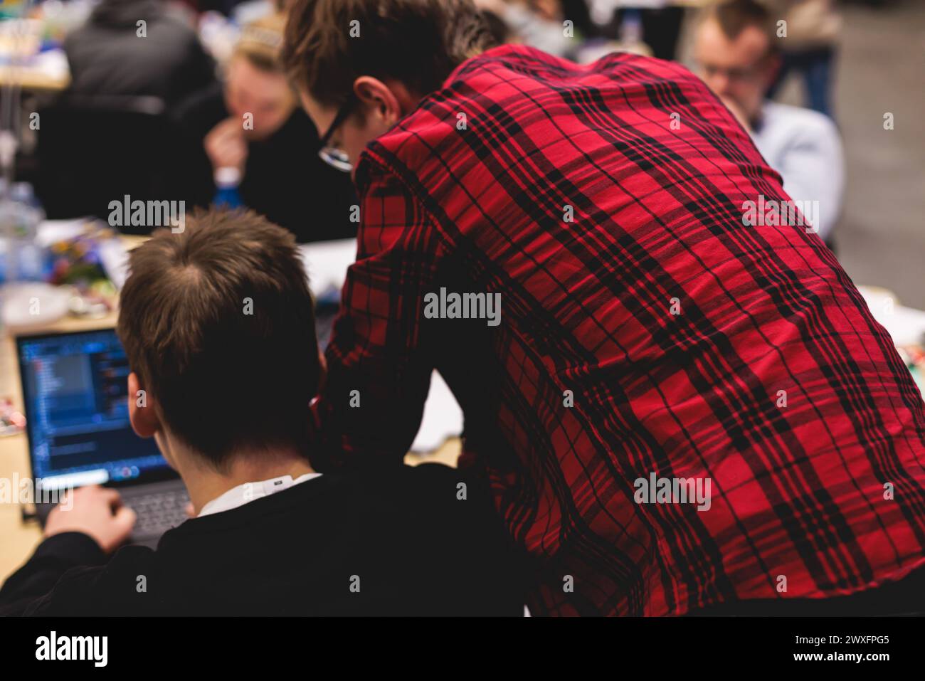 Software developer students in auditorium hall working on computer and ...