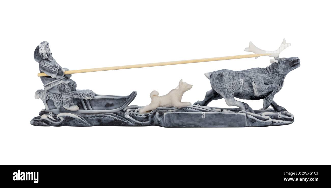 Evenk rides a reindeer sled with a dog running alongside. Miniature figurine, souvenir. Isolated on white background Stock Photo