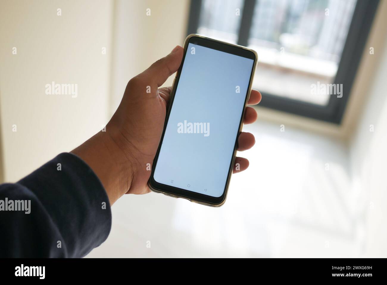 pov of hand using phone showing white screen in empty room Stock Photo