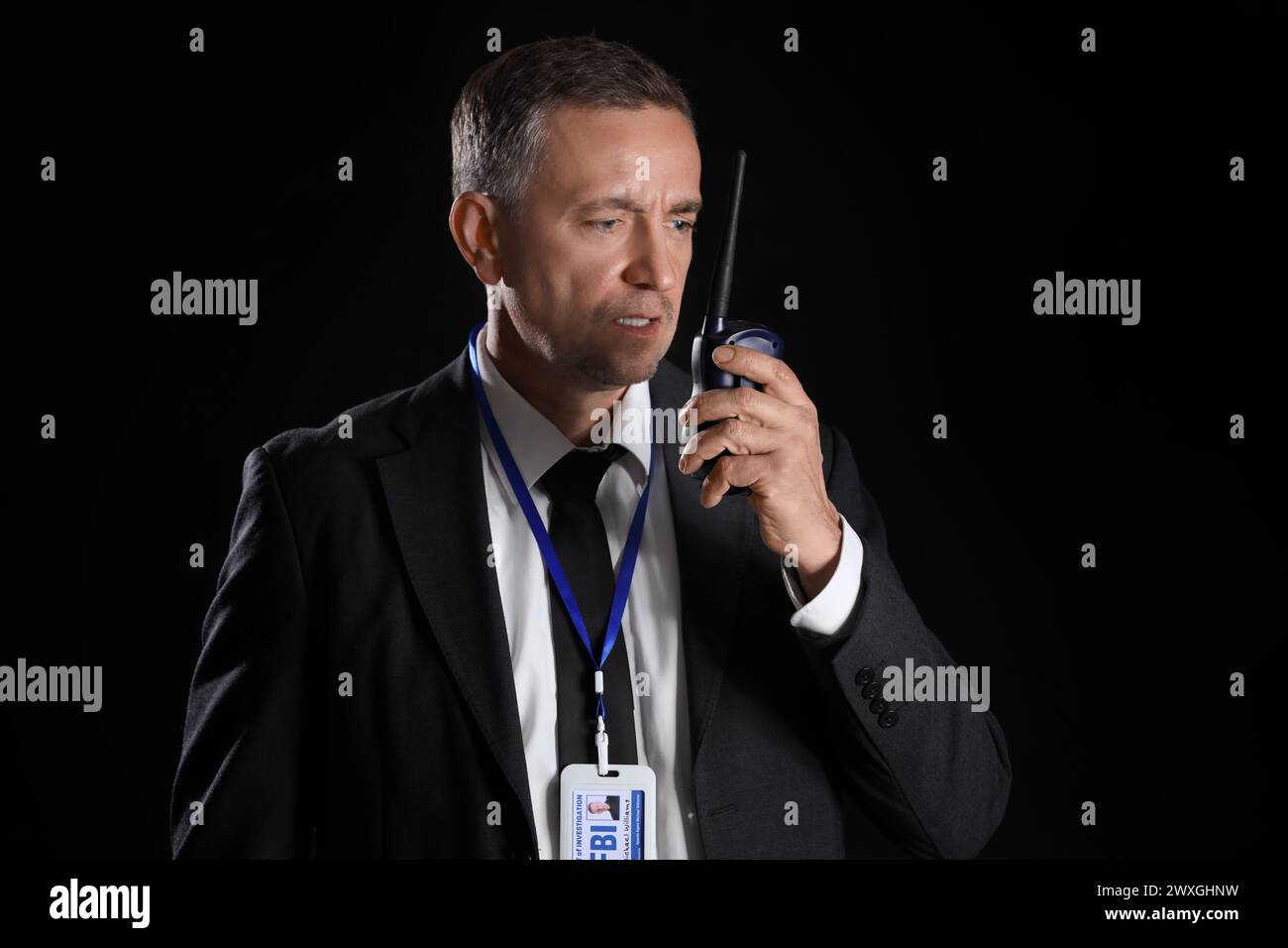 Mature FBI agent with two-way radio on black background Stock Photo - Alamy