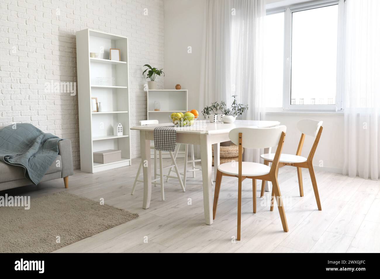 Interior of light room with dining table and shelf units Stock Photo ...