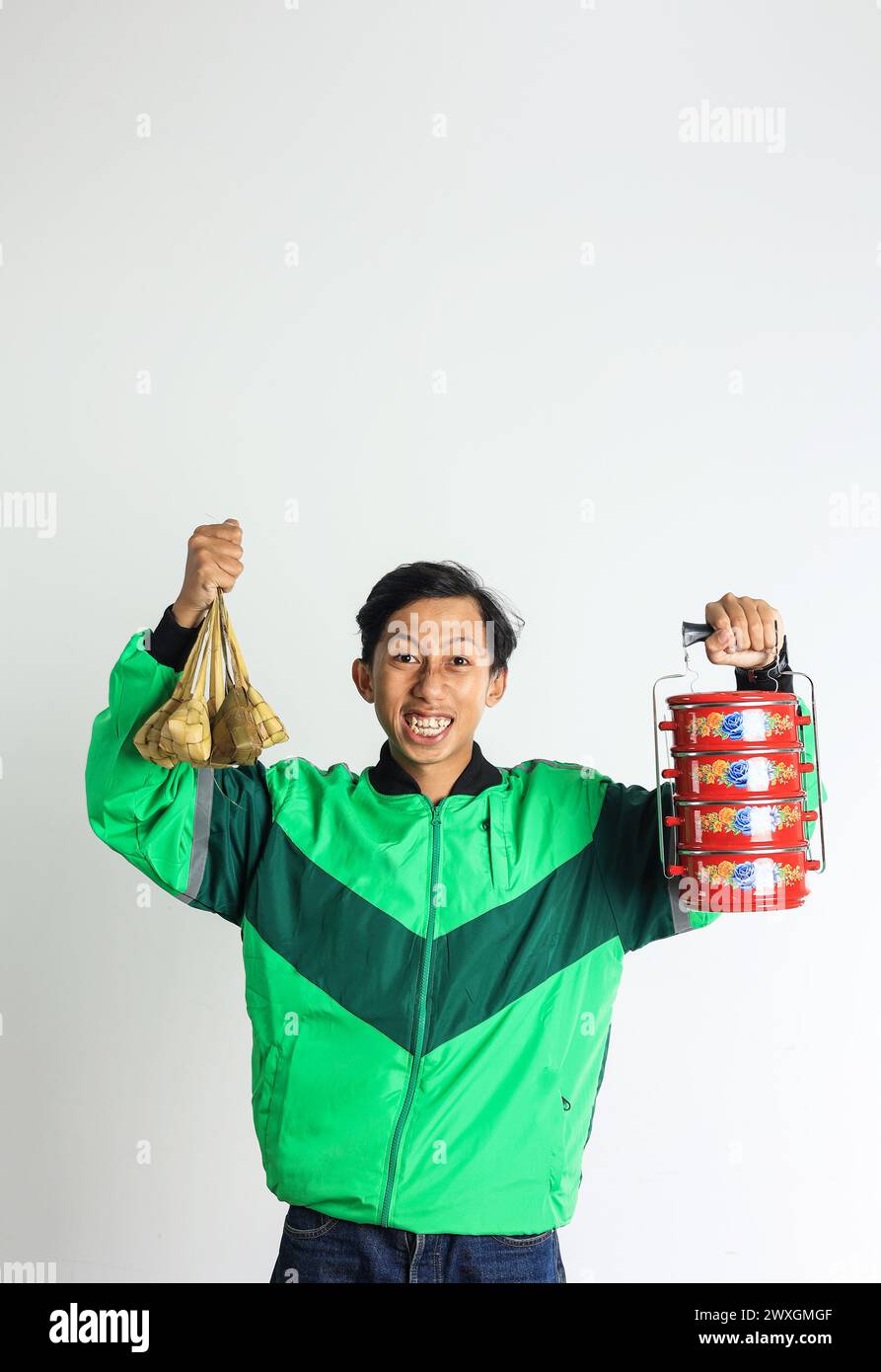Asian Male Online Driver Excited Delivering Ketupat and Side Dish on Stackable Lunchbox or Rantang, Eid Mubarak Hampers Concept Stock Photo