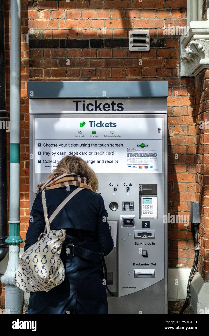 Leatherhead Surrey, UK, March 30 2024, Woman Alone Buying Ticket At Railway Station Automated Ticket Machine Stock Photo