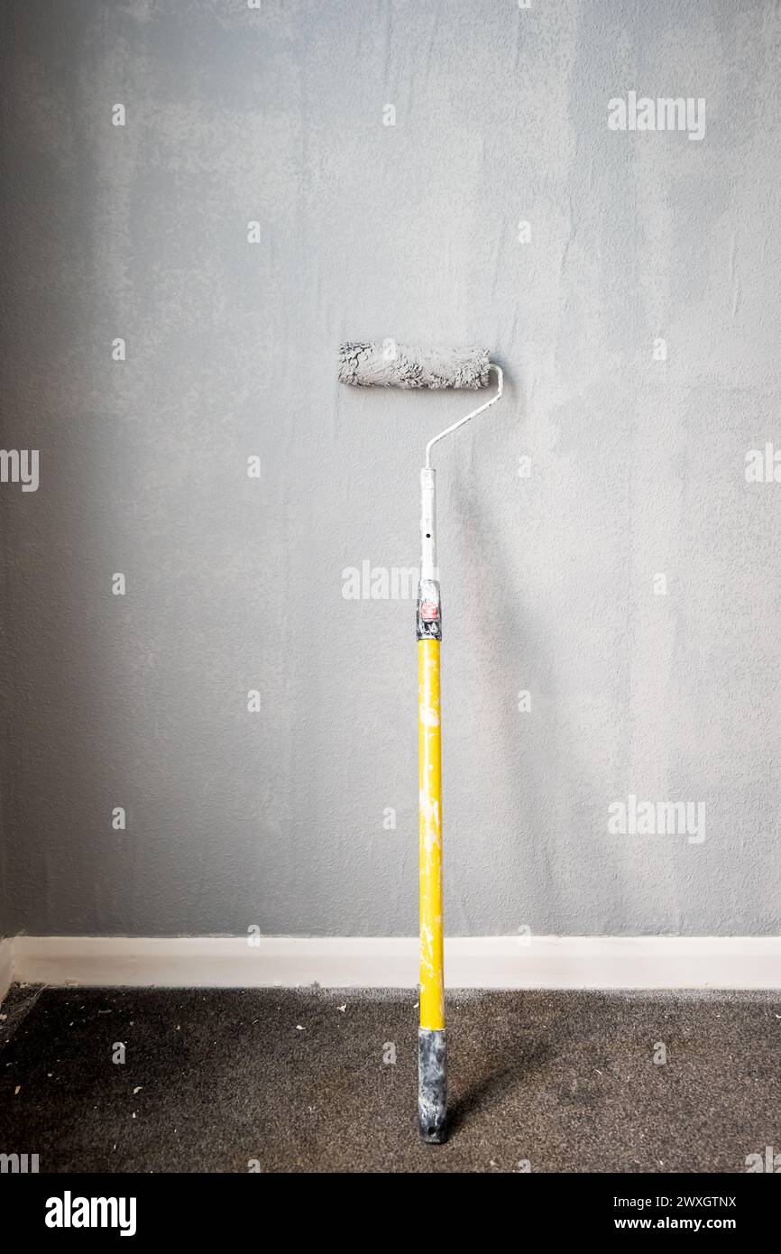 Paint roller extendable pole over painted woodchip wallpaper wall