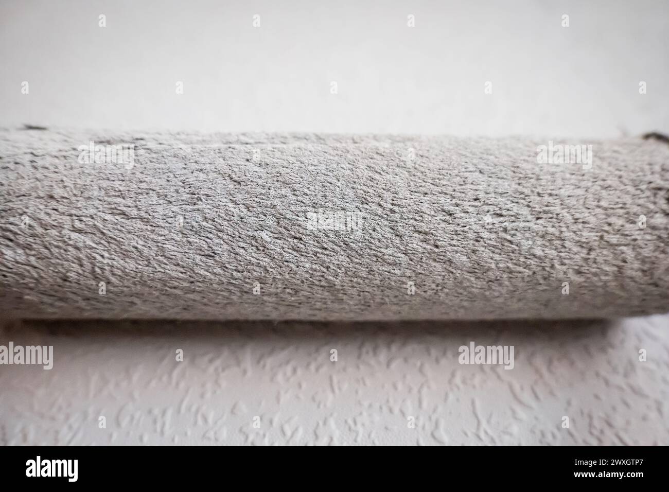 Paint roller extendable pole over painted woodchip wallpaper wall